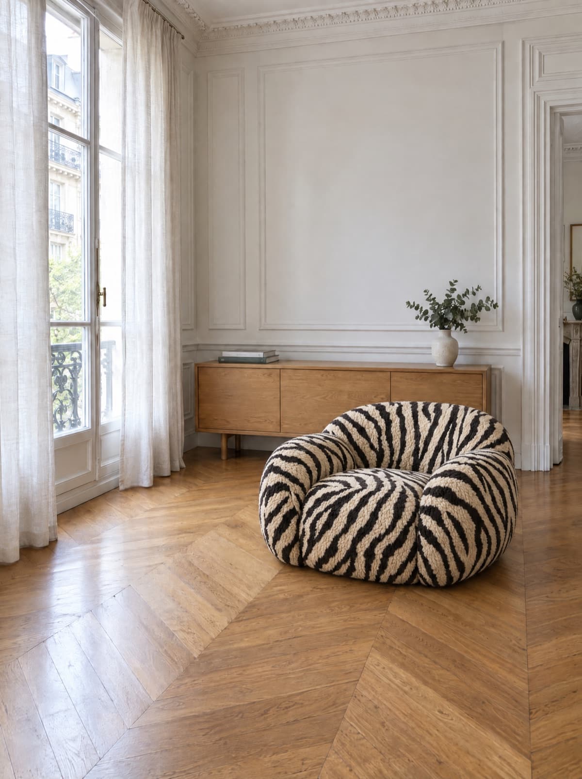 The same living room, with the zebra armchair standing on the parquet in front of the sideboard