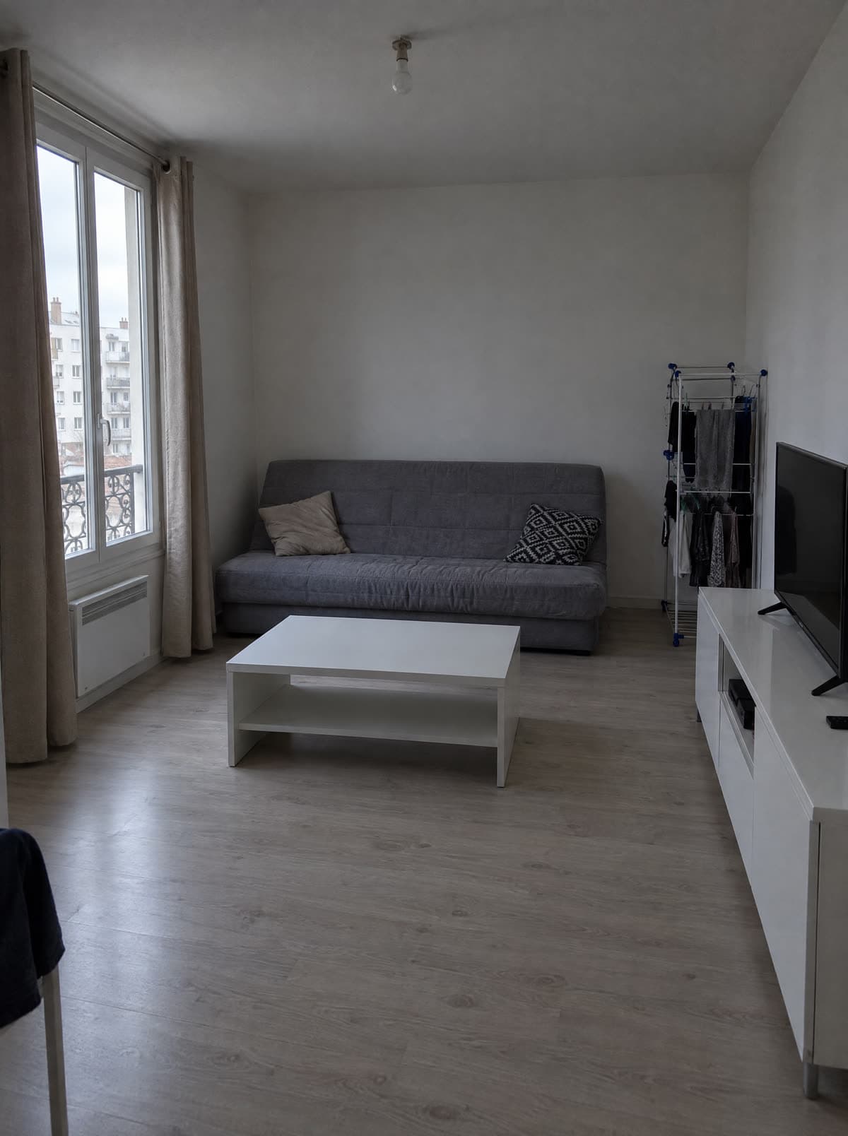 A living room before: gray sofa, white coffee table, bare walls